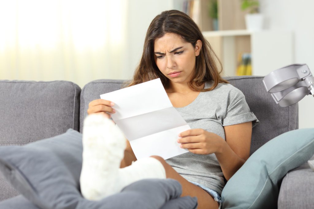 Worried disabled woman reading a letter sitting on a couch in the living room at home