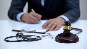 Judge signing lawsuit, banging gavel near stethoscope